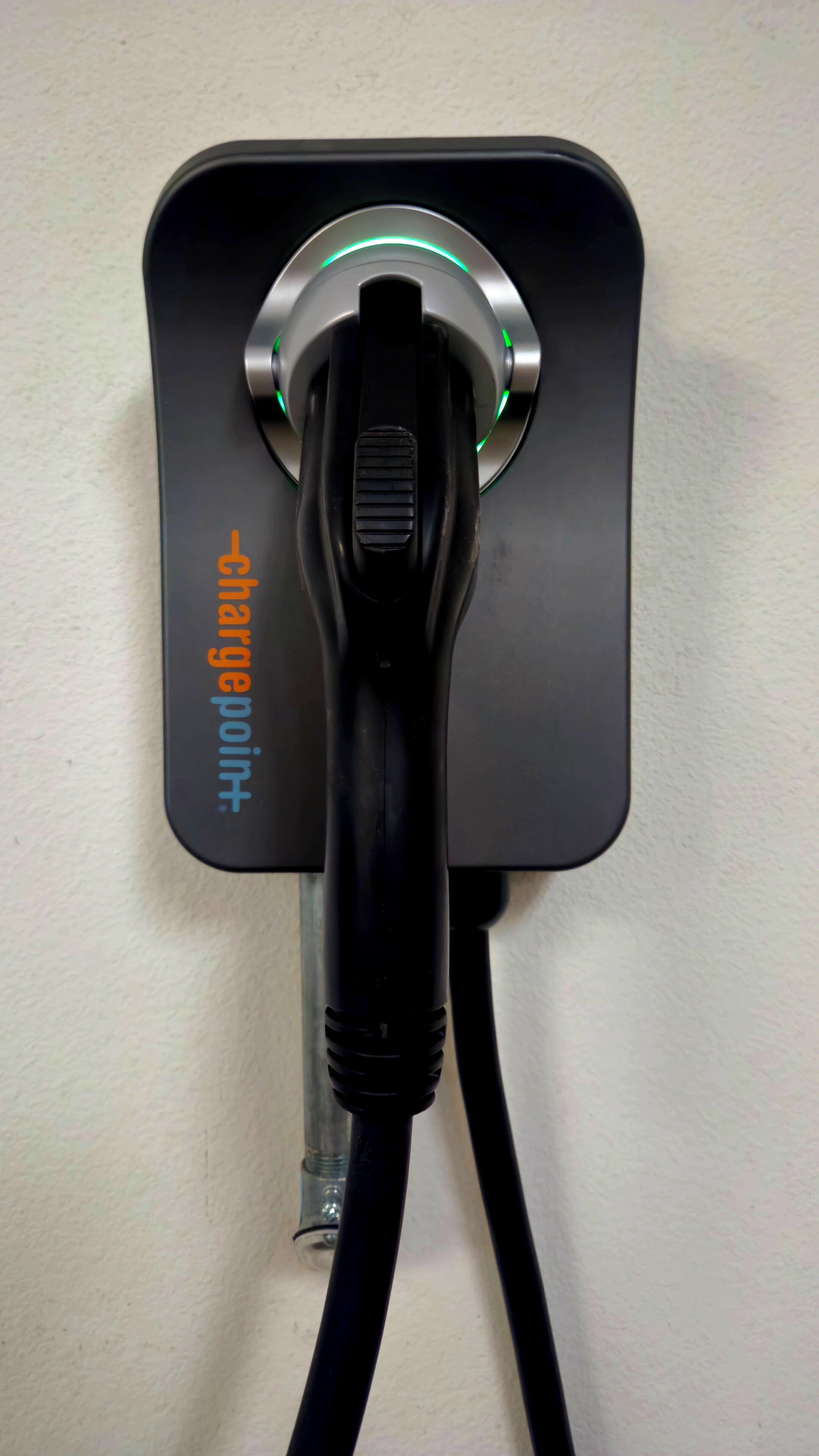 A wall-mounted charging station with a cable plugged in.