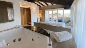 A modern bathroom with a large bathtub, a shower area, and a view of the sea through large windows. - Resort Hotel Tamerici (Marciana Marina)