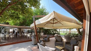 An outdoor patio with wicker furniture and a covered seating area. - Resort Hotel Tamerici (Marciana Marina)