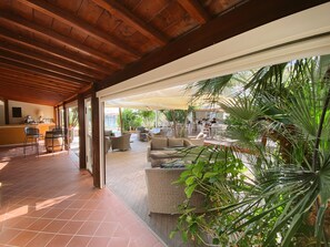 A covered outdoor seating area with wicker furniture and a bar area. - Resort Hotel Tamerici (Marciana Marina)