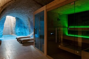 A modern spa with a glass-enclosed sauna, a stone-tiled floor, and a wooden ceiling. - Le Carasse Boutique Hotel (Mola di Bari)