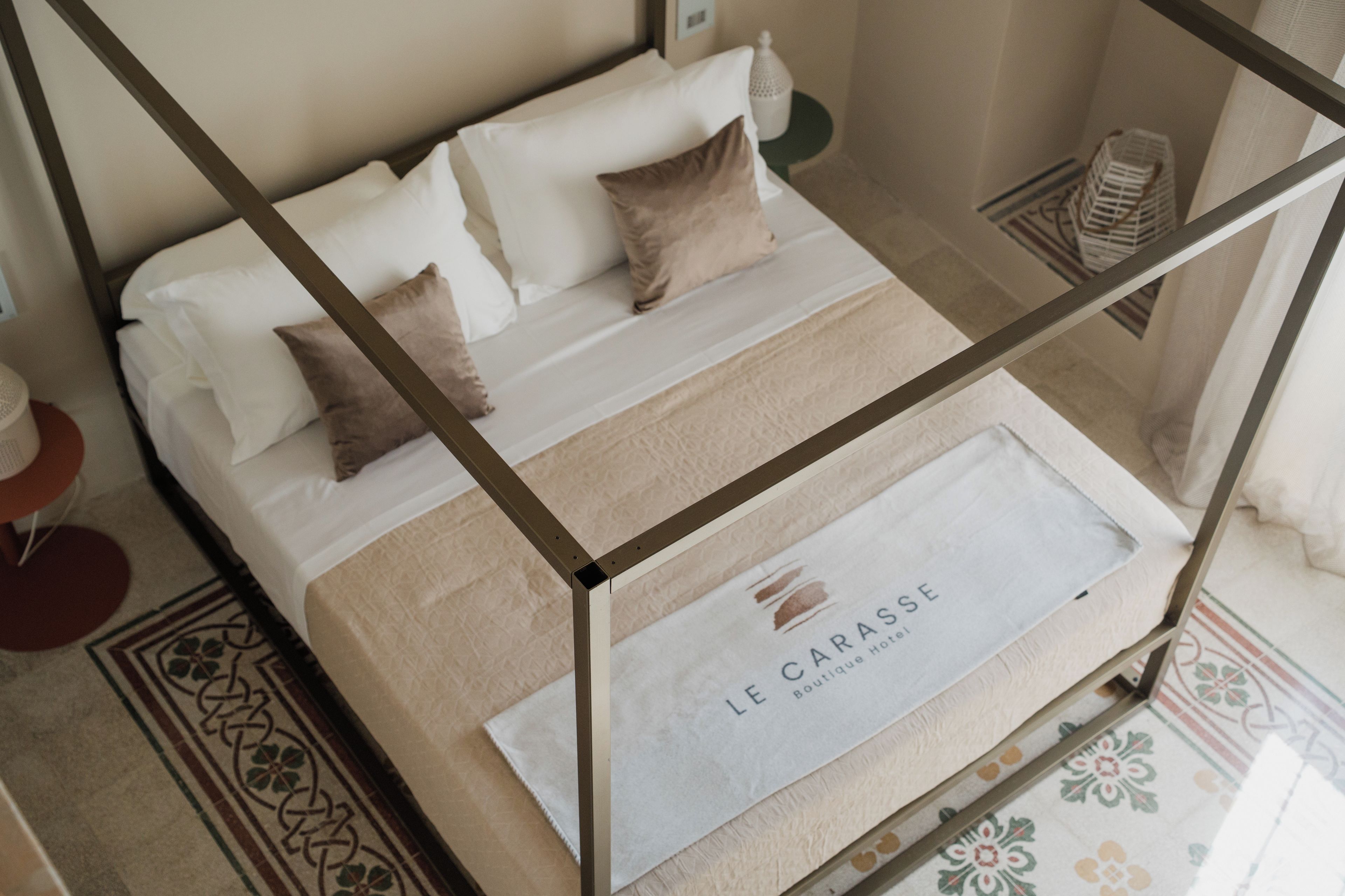 A neatly made bed with a headboard, a bedside table, and a decorative rug.
