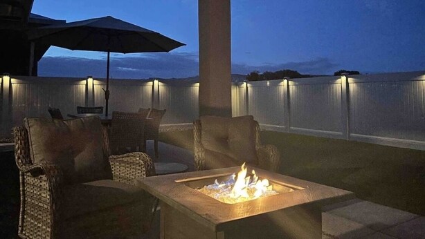 An outdoor seating area with a fire feature, wicker furniture, and a view of the ocean at dusk. - Spectacular Mesa view 3 room home  (Grand Junction)
