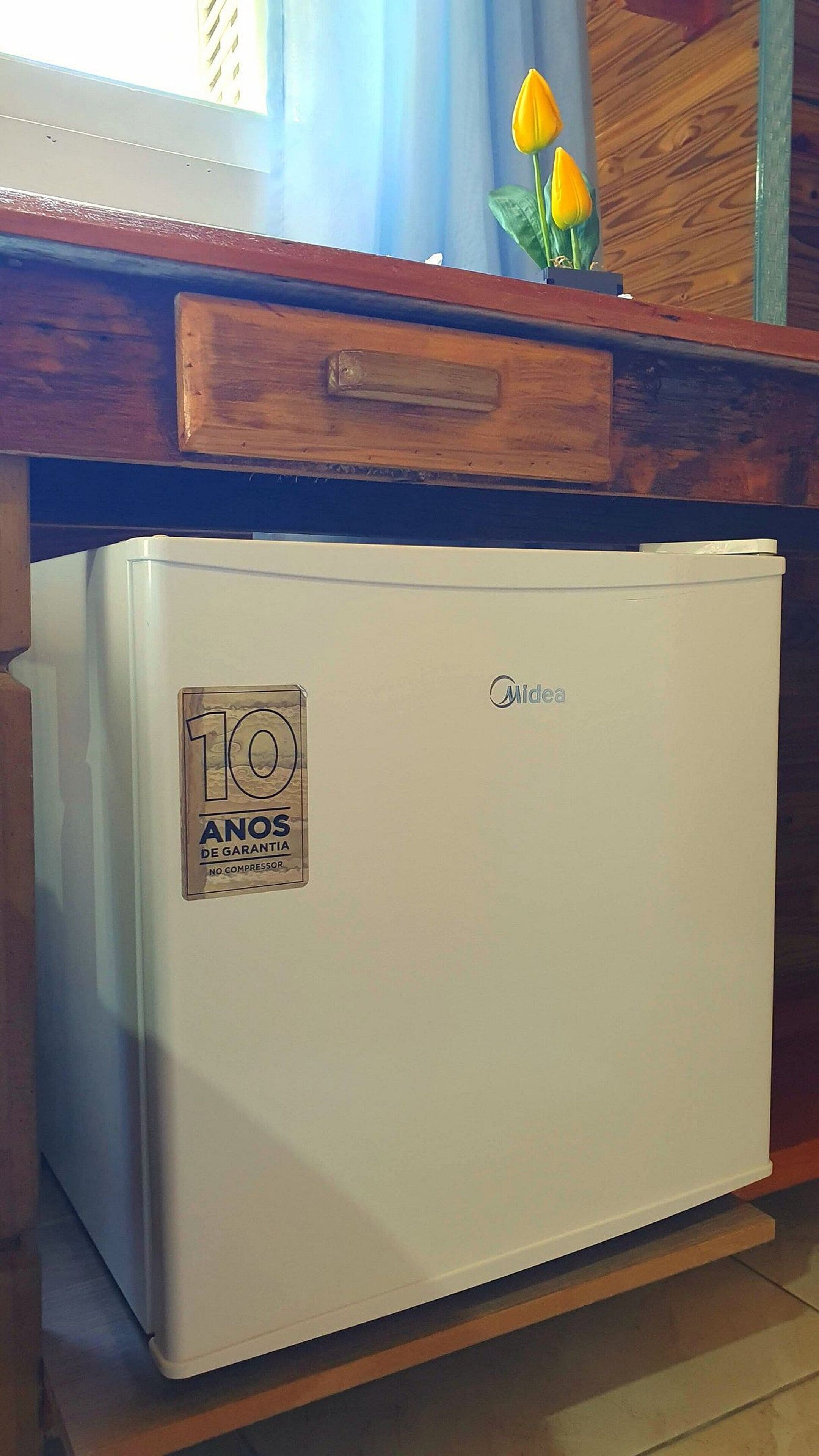 Ein kleiner, weißer Kühlschrank mit Aufkleber, der eine 10-jährige Garantie bezeugt.