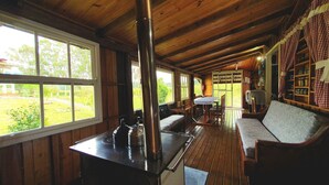 A cozy cabin interior with a wooden interior, a dining area with a table and chairs, and a view of the outdoors through large windows. - Pousada Mato Verde - Urubici - SC (Urubici)