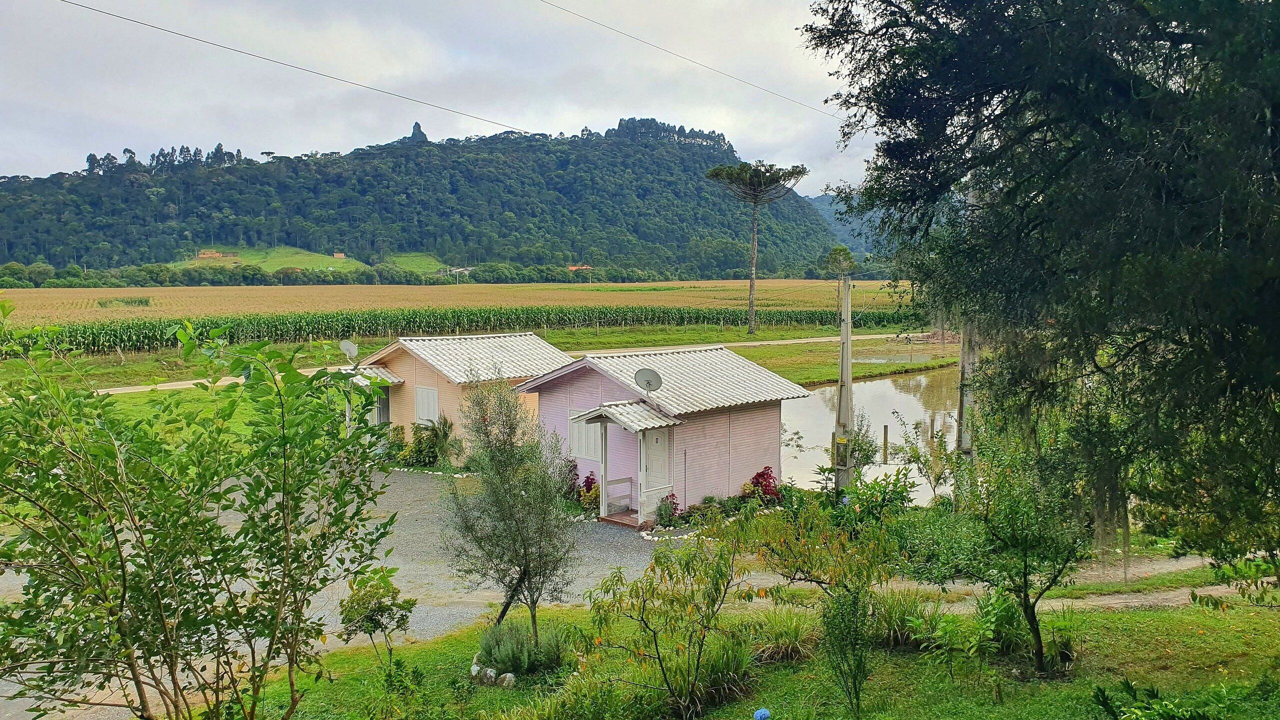 A rural setting with two small buildings, a field, and a hill in the background.