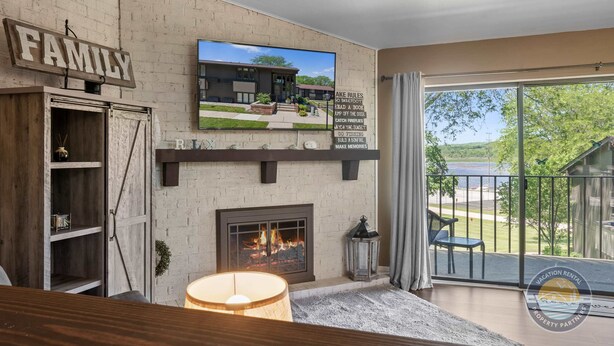 Een moderne woonkamer met een open haard, een aan de muur bevestigde televisie en een balkon met uitzicht op de omgeving.