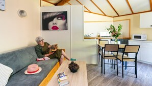 Un salon confortable avec un canapé, une table à manger et des chaises, un coin cuisine et un tableau accroché au mur.