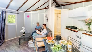 A compact living space with a kitchenette, a dining area, and a seating area with two people reading.