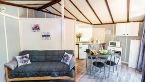 A compact living space with a sofa, dining table, chairs, and a kitchenette.