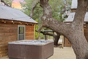 A wooden cabin with a hot tub and string lights.