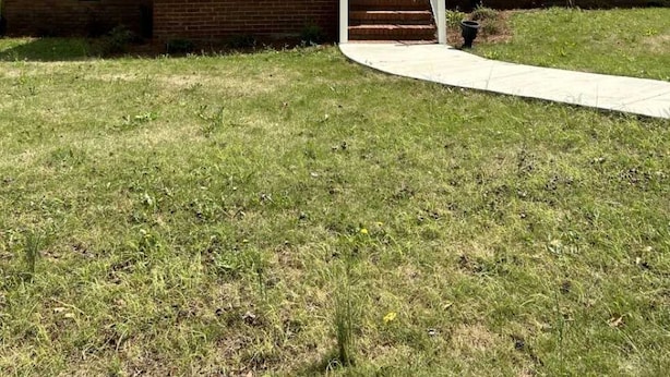 A single-story house with a front porch, a chimney, and a brick foundation.