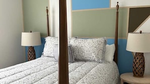 A bedroom with a large bed, two bedside tables with lamps, and a geometric-patterned wall.