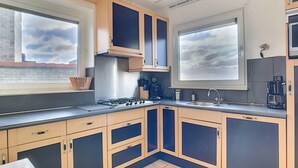 Een moderne keuken met lichte houten kastjes, een roestvrijstalen fornuis en een groot raam.