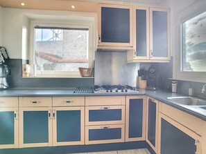 Una cocina moderna con estufa a gas, electrodomésticos de acero inoxidable y alacenas de madera clara.