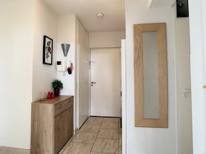 A hallway with a wooden cabinet, a door, and a wall-mounted light fixture.