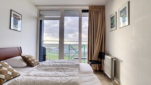 Een hotelkamer met een groot bed, uitzicht op een groen landschap door het raam en een radiator aan de muur.