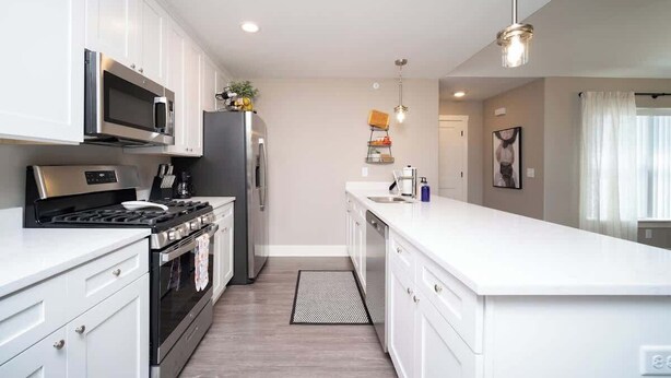 A modern kitchen with white cabinetry, stainless steel appliances, and a central island. - Charming 3 bedroom Condo in Bettendorf with King Master Suite (Bettendorf)