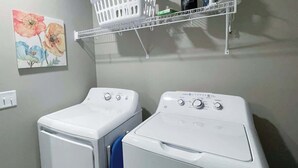 A laundry area with two white front-loading washers and a white shelf above them. - Charming 3 bedroom Condo in Bettendorf with King Master Suite (Bettendorf)