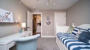 A bedroom with a bed, a desk, a chair, a ceiling fan, and a wall with a Route 66 sign. - Charming 3 bedroom Condo in Bettendorf with King Master Suite (Bettendorf)