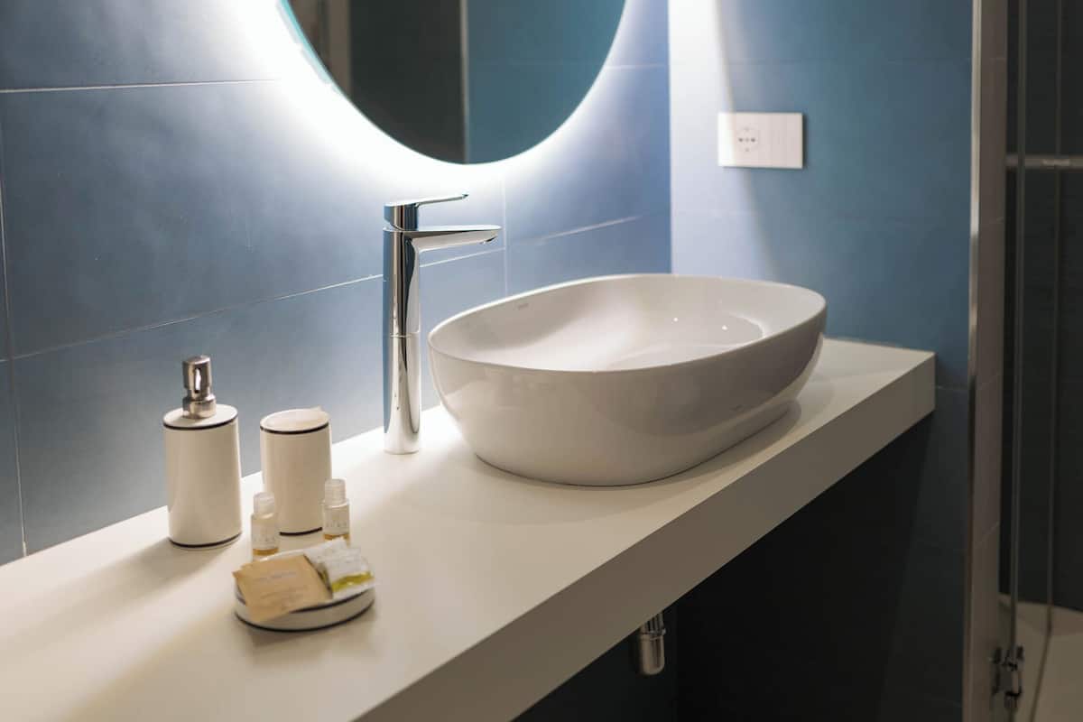 Un baño moderno con un espejo redondo, un lavabo blanco y una zona de ducha.