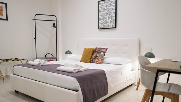 Um quarto moderno com uma cama grande, uma mesa de cabeceira, uma cadeira e uma escrivaninha.