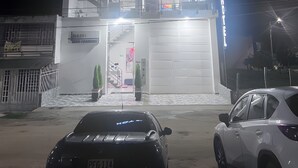 Een meerlaags hotel met een opvallend “HOTEL” bord, een zichtbare garagepoort en een parkeerplaats met auto's.