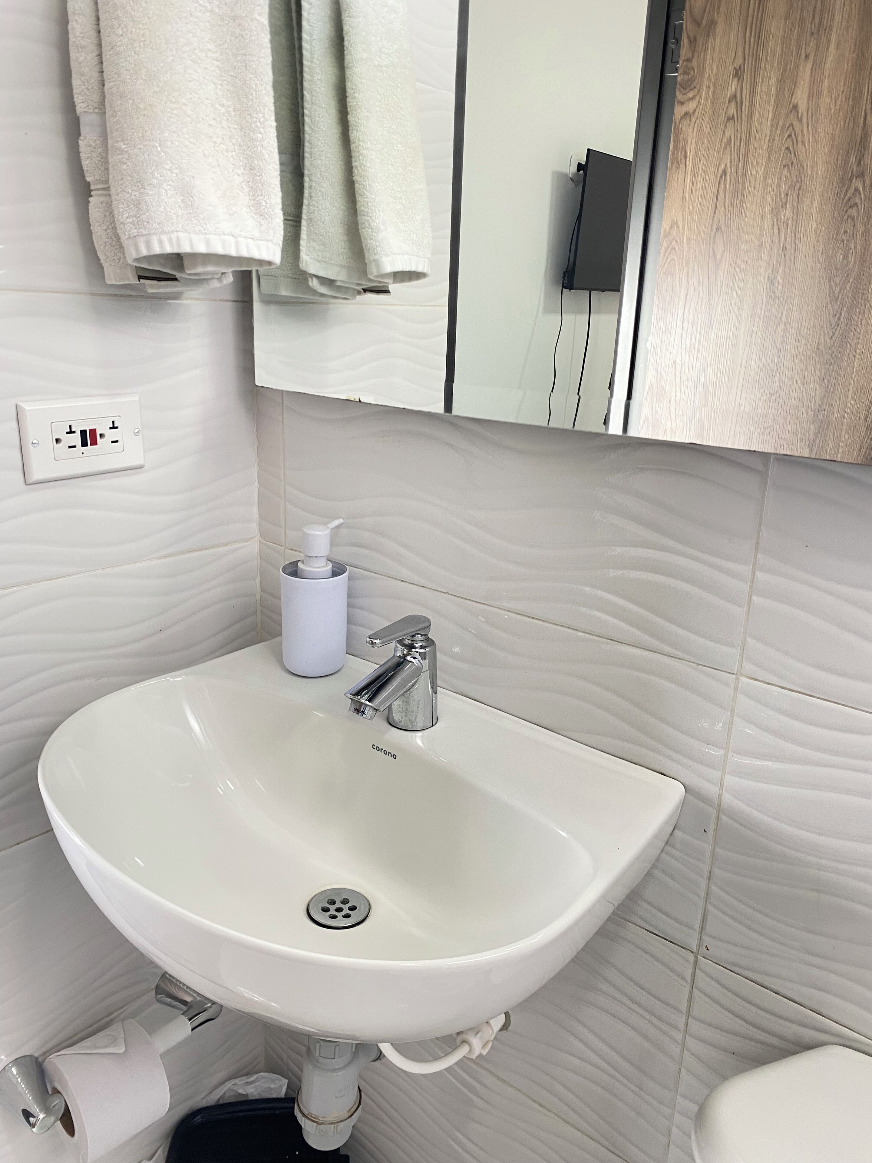 A bathroom with a white sink, a mirror, and a towel rack.