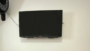 Een modern bureau met een stoel, een flatscreen televisie aan de muur en een stopcontact.