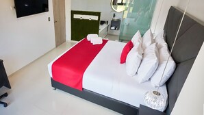 Een moderne hotelkamer met een groot bed, een flatscreen-televisie, een douchecabine van glas en een kleine badkamer met een ronde spiegel.