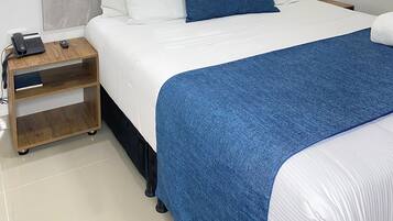 Una habitación de hotel ordenada con una cama, mesitas de noche y dos lámparas colgantes.