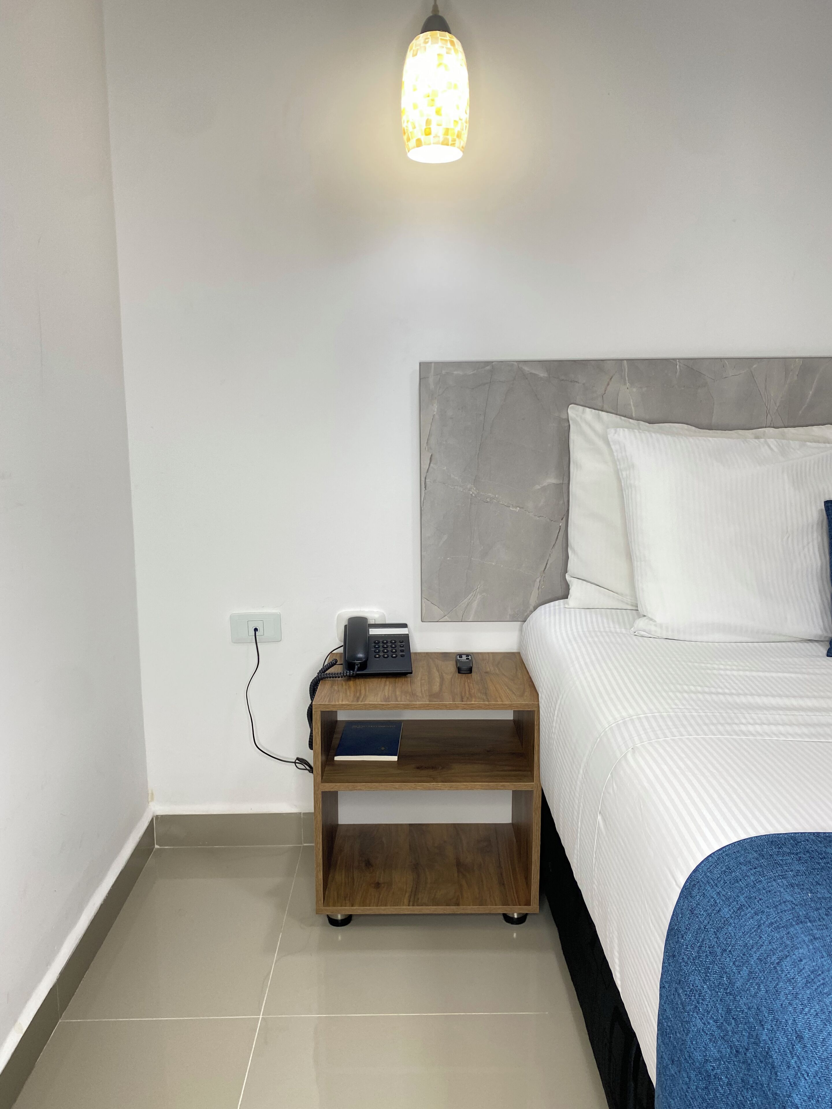 A neatly arranged bedroom with a bed, bedside table, and a lamp.