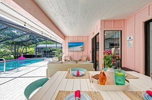 Un espace aménagé au bord de la piscine, avec une table à manger, des chaises et une vue sur la piscine.