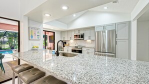 Una cocina moderna con encimera de granito, electrodomésticos de acero inoxidable y una isla grande con taburetes de bar.
