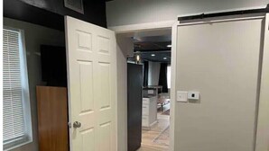 A hotel room with a bed, a wardrobe, a small trash bin, and a window with blinds. - Newly Renovated Downtown Gem! (Buffalo)