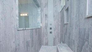 Une petite salle de bain carrelée, avec un banc, un miroir et un espace douche.