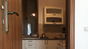 Une cuisine avec des meubles blancs, une bouilloire et un four à micro-ondes.