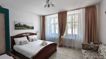 A bedroom with a wooden bed, a sofa, a painting on the wall, and a ceiling fan.