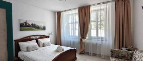 A bedroom with a wooden bed, a sofa, a painting on the wall, and a ceiling fan.