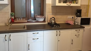 Une cuisine avec des meubles blancs, une bouilloire sur la cuisinière, un four à micro-ondes et une machine à café.