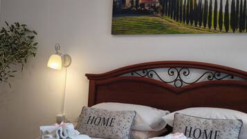 A neatly made bed with pillows labeled 'HOME' and a painting of a landscape on the wall.