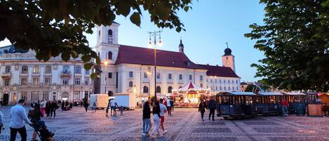 A historic square with cobblestone pavement, a prominent clock tower, and a festive market.