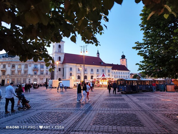 A historic square with cobblestone pavement, a prominent clock tower, and a festive market. - Buon Studio Sibiu, near train station and Small Square Old Town (Sibiu)