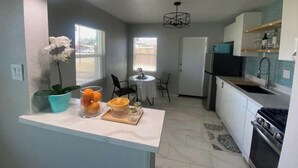 A compact kitchen with a central island, a dining area with a table and chairs, and a refrigerator. - Little Blue Box  (Phoenix)