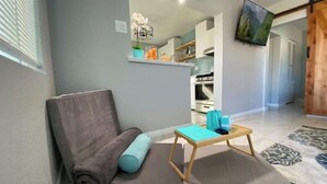 A modern living room with a sofa, a small table, and a TV mounted on the wall. - Little Blue Box  (Phoenix)