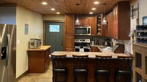 Una cocina amplia con techo alto, vigas de madera y una isla grande con taburetes de bar.