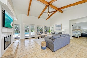 A spacious living room with a large grey sofa, a fireplace, and a ceiling fan.