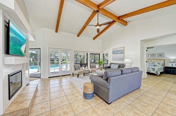 A spacious living room with a large grey sofa, a fireplace, and a ceiling fan.