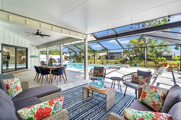 Une terrasse extérieure couverte avec une piscine, un coin salon et une table à manger.