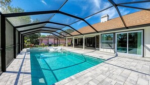 En inomhuspool med kristallklart blått vatten, omgiven av en modern arkitektonisk struktur med glasdörrar och ett kaklat golv.